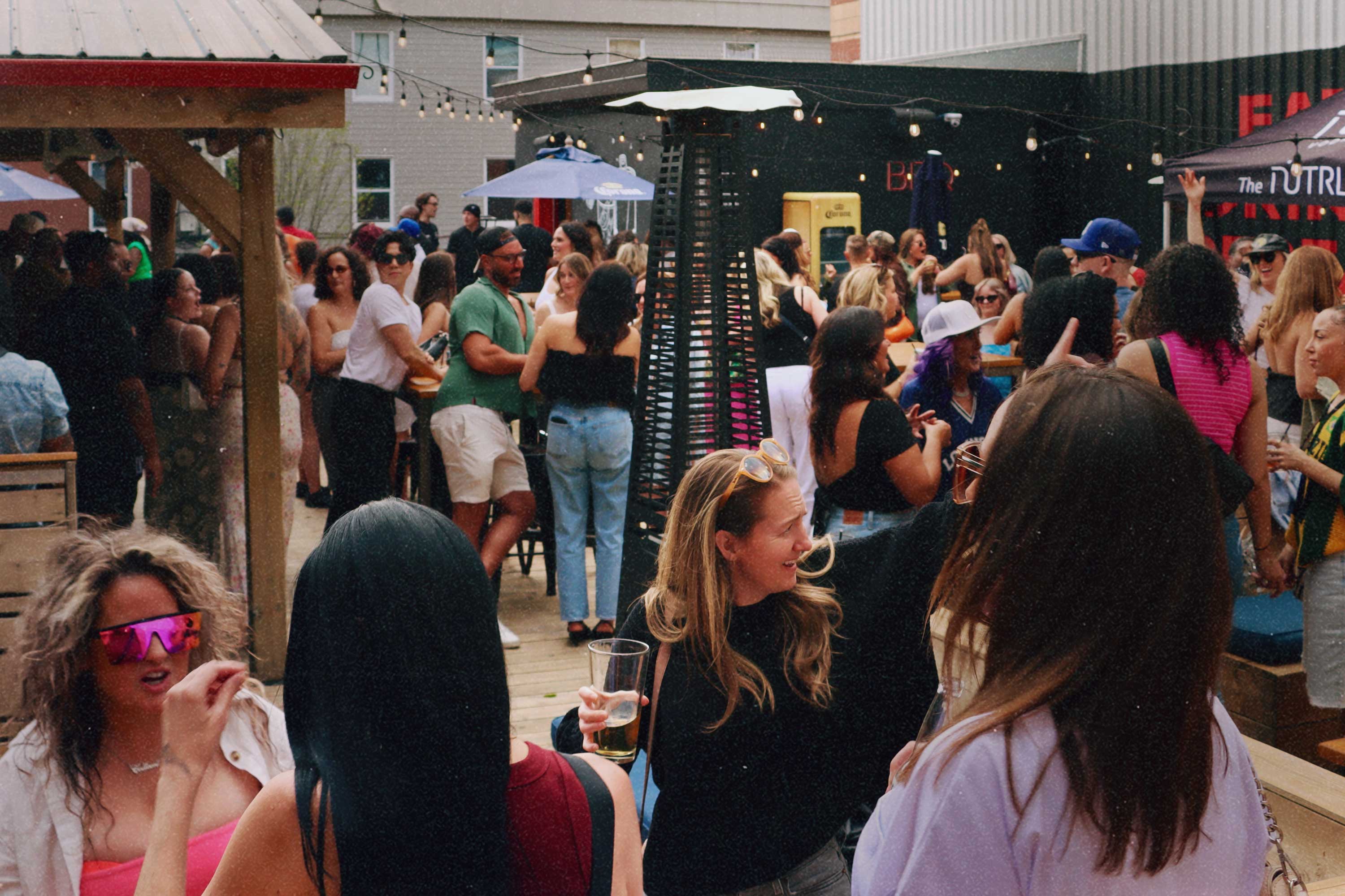 Wide view of a crowded outdoor patio party under string lights