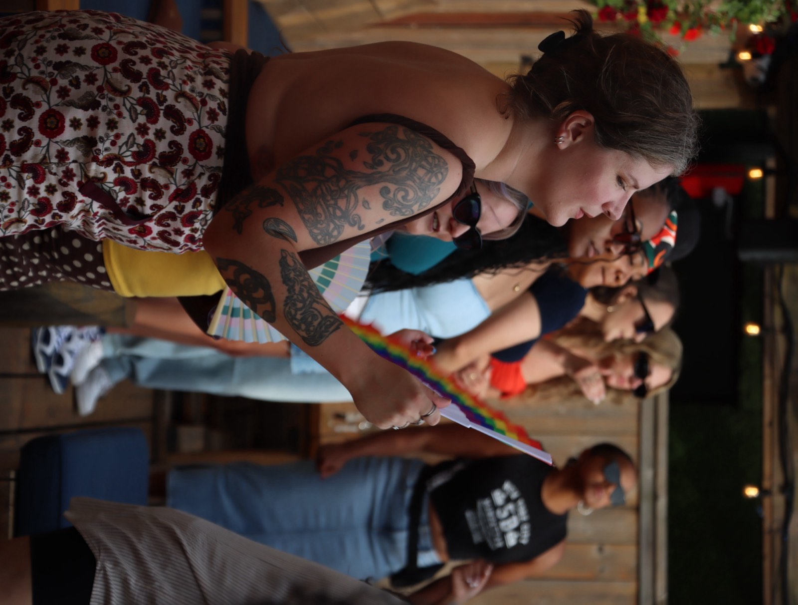 A guest waves a rainbow-colored fan while catching up with friends at the day party