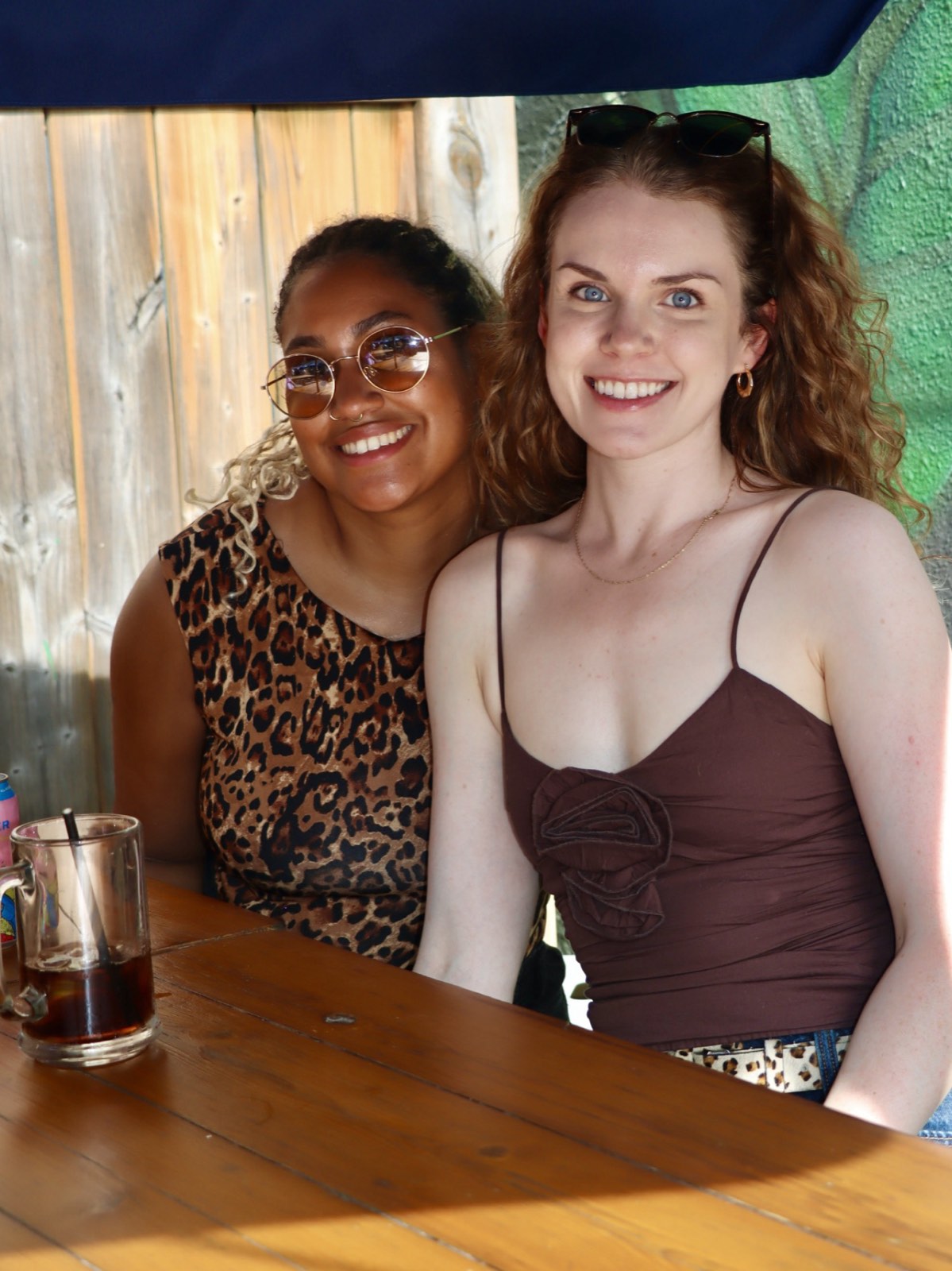 Two friends smiling together at a sunny patio table