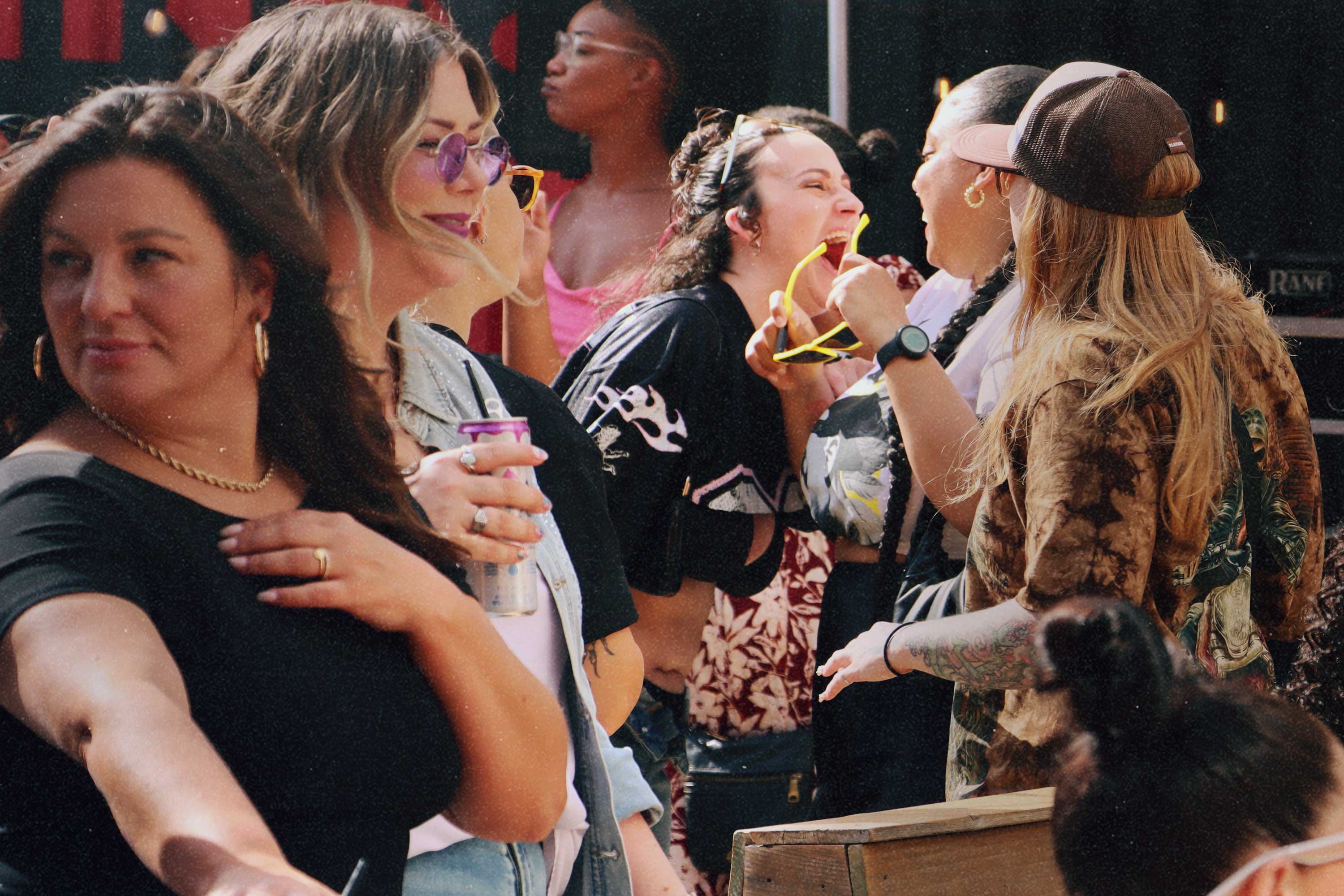 Friends laughing together in the sun at a Bump & Grind patio party